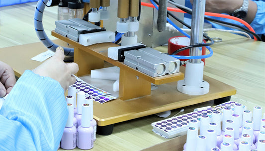 Operator applying circular shade labels to light purple gel polish bottle caps before packing
